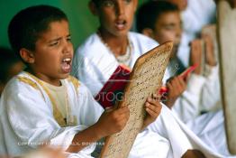 Image du Maroc Professionnelle de  Sous une tente on découvre la méthode traditionnelle de l’enseignement et l’apprentissage du saint coran prodigués aux enfants. Les jeunes récitent les sourates devant le Fkih (instituteur) qui écoute attentivement les versets ainsi récités, Samedi 18 septembre 2006, aux environ de Tan Tan dans un site désertique sur lequel la ville, a toujours accueilli la majorité des tribus et des grandes familles nomades du désert lors d'un grand Moussem, danses chants, course de chameaux et fantasia font partie des festivités. (Photo / Abdeljalil Bounhar)

 